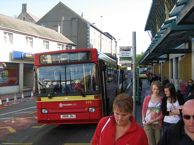 a bus on a scruffy street with people in caernarfon